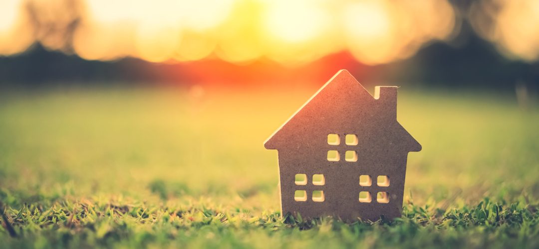 Copy space of home and life concept. Small model home on green grass with sunlight abstract background. Vintage tone filter effect color style.